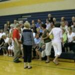 Photographer getting us ready for our class photo...Kay German Bun in striped navy top, Leigh Ann Willard Hackney starting to sit, and Debbie Freeman Neustadt heading to bleachers for a seat